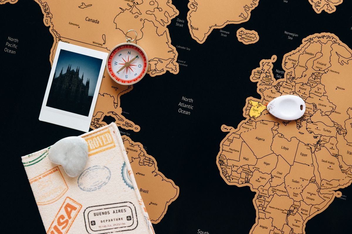Flat lay of a map, compass and travel photographs used for planning a trip